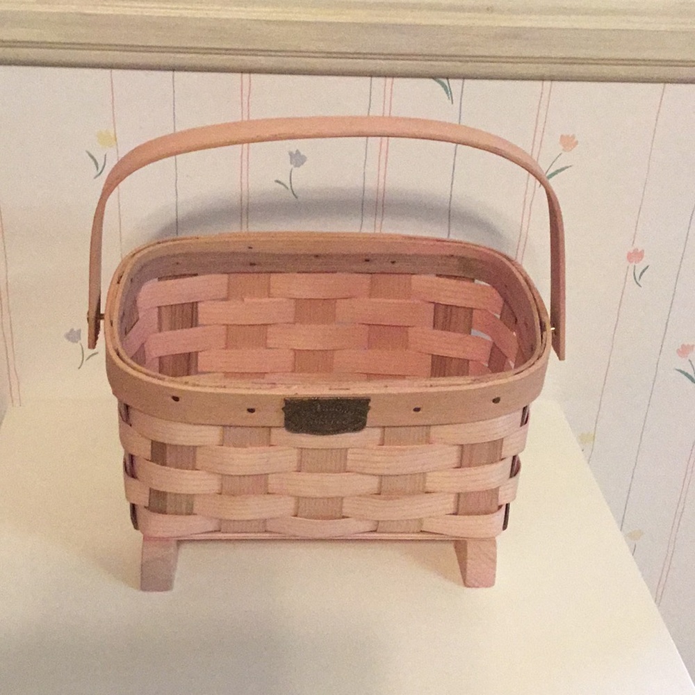 Pink peterboro basket with handle and feet.